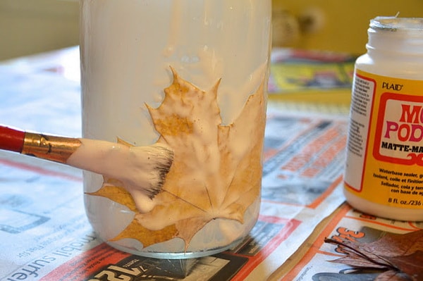 Pegando hojas secas sobre un frasco de vidrio