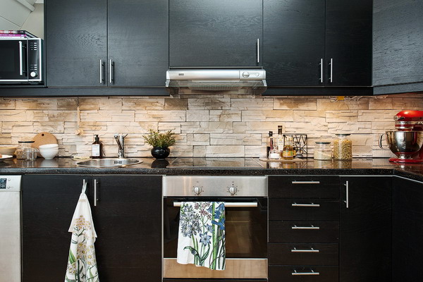 Muebles de cocina negros y pared de piedra