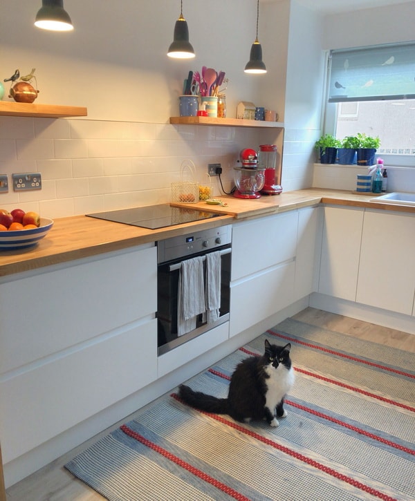 Cocina blanca con encimera de madera y gran alfombra