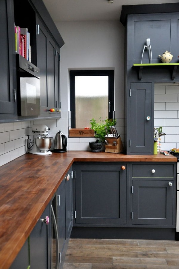 Muebles de cocina negros, pared blanca y encimera de madera