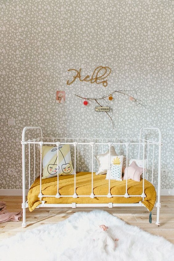 Cuna de hierro forjado y papel pintado en el dormitorio del bebé