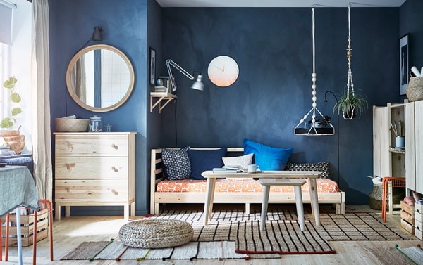 Dormitorio con paredes azules oscuras y muebles de madera clara