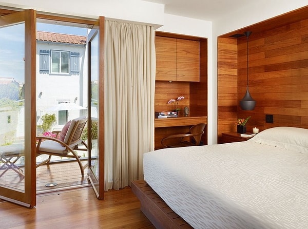 Mucha madera en dormitorio pequeño con balcón