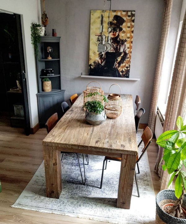 Comedor con mesa de madera, lámpara de estilo industrial y un gran cuadro en la pared