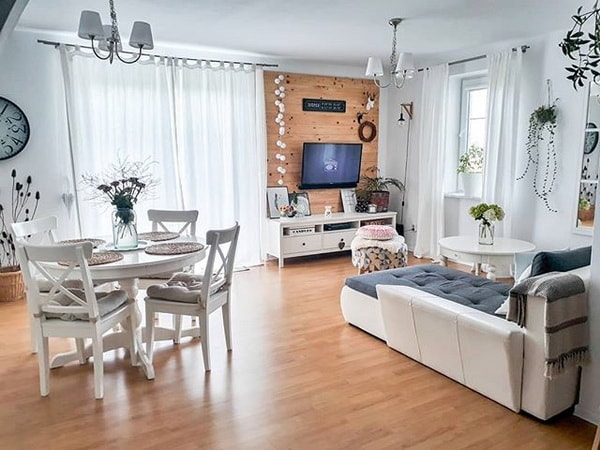 Salón comedor con suelo de madera y muebles blancos