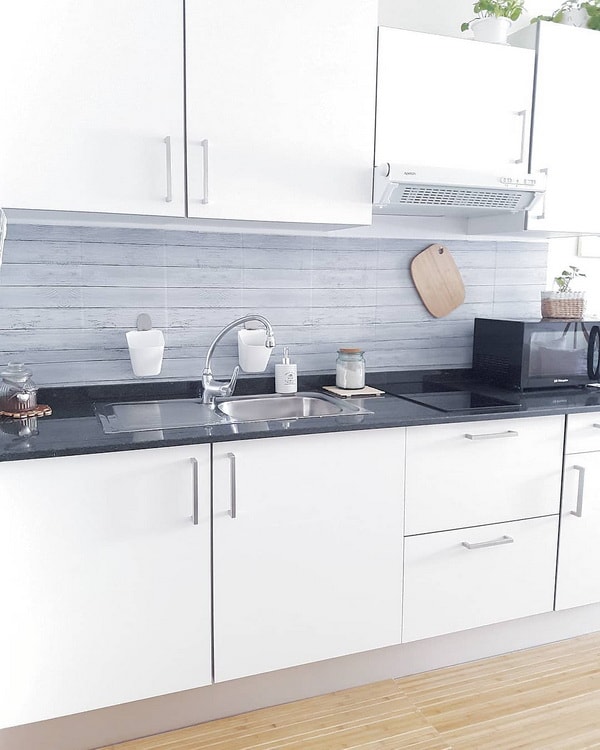Cocina pequeña con muebles blancos y encimera de granito negra