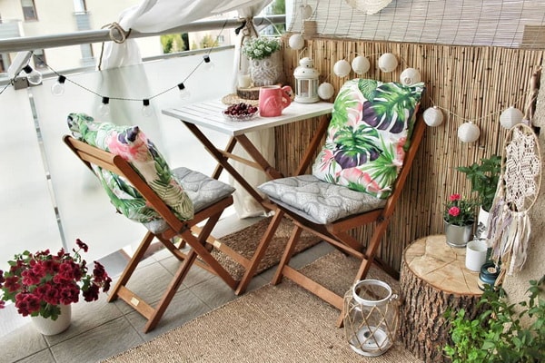 Pequeño balcón con muebles plegables de madera y fibras naturales