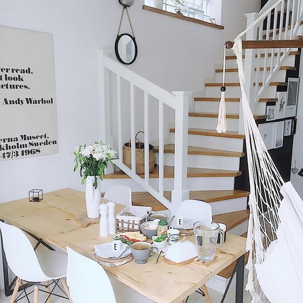 Mesa de madera natural en tono claro y sillas de diseño blancas