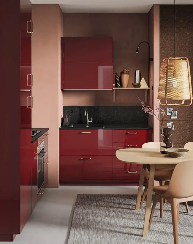 Muebles de cocina en color granate y mesa en madera clara