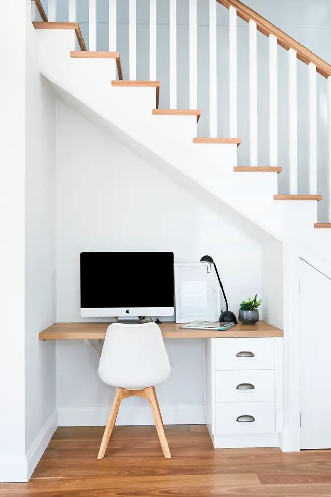 Un escritorio bajo escalera en blanco y madera
