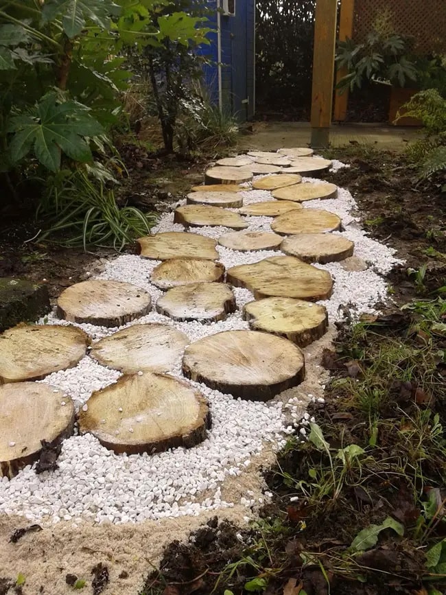 Pequeño camino de jardín con troncos y piedras Pequeño camino de jardín con troncos y piedras