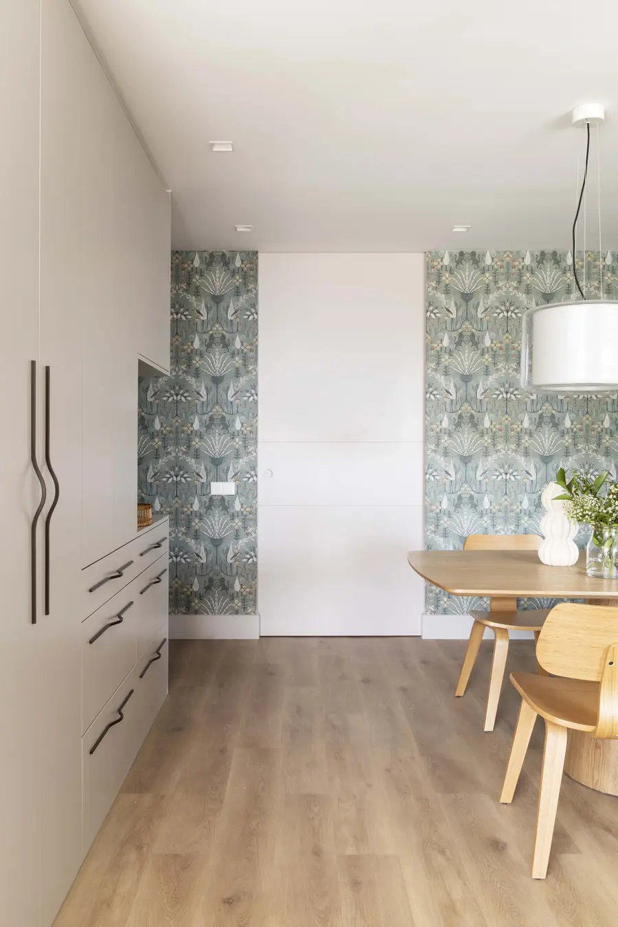 El comedor amplía visualmente la entrada de la vivienda Comedor con mesa de madera, lámparas suspendidas y mueble con espejo