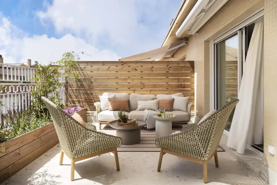 La terraza como extensión del salón Salón exterior de la terraza con sofá, butacas y cerramiento de madera