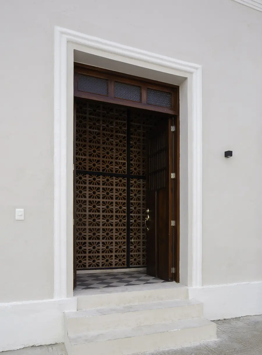 Acceso principal con celosía de barro Entrada de Casa Luciérnagas con puerta de madera y celosía de barro