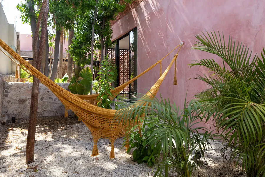 Un rincón de descanso junto al jardín Hamaca artesanal entre la vegetación del patio de Casa Luciérnagas