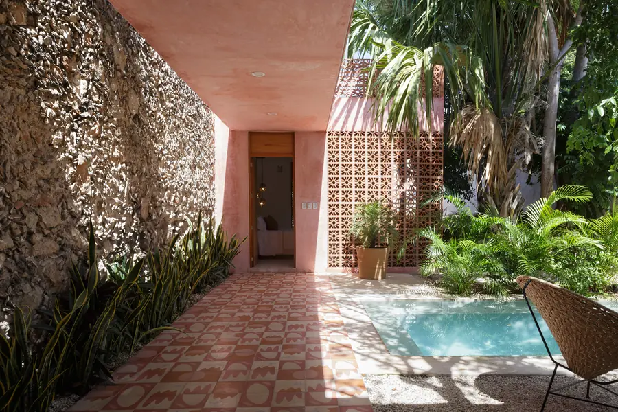 Un recorrido entre piedra, vegetación y celosía Pasillo de Casa Luciérnagas junto al jardín con muro de piedra y celosía