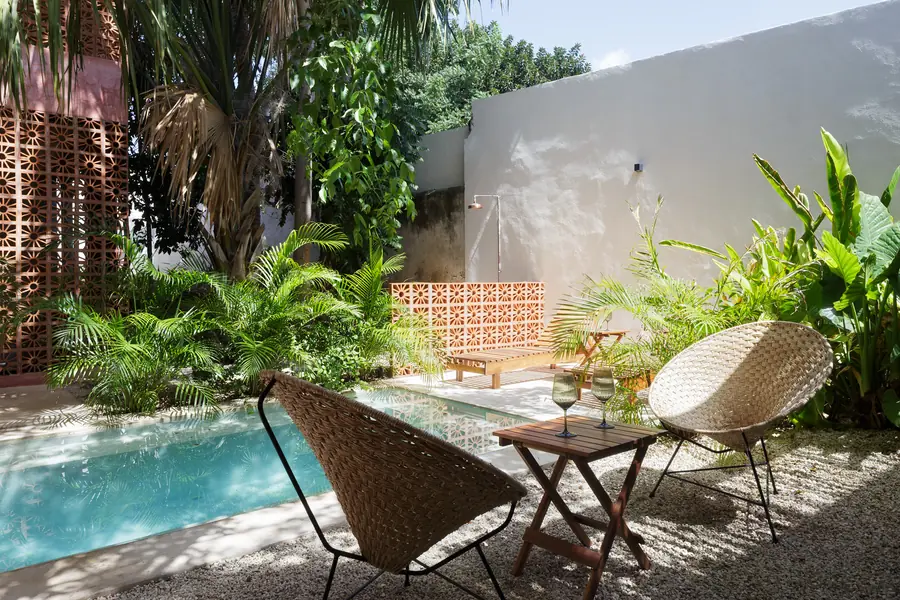 Vegetación y piedra alrededor de la piscina Patio tropical de Casa Luciérnagas con piscina y muros de mampostería