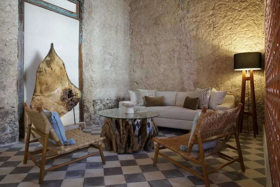 Texturas originales y mobiliario cálido en el salón Salón de Casa Luciérnagas con muros de piedra y mobiliario de fibras naturales