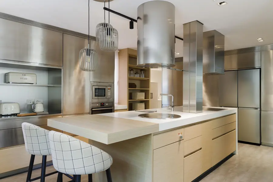 Una cocina integrada mediante pequeños cambios Cocina de la reforma Darder con isla, taburetes tapizados y acabados en roble