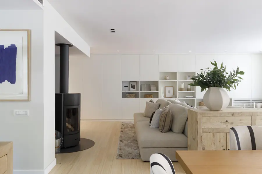 Rincón de estar de la vivienda Darder con chimenea, sofá y mueble librería a medida