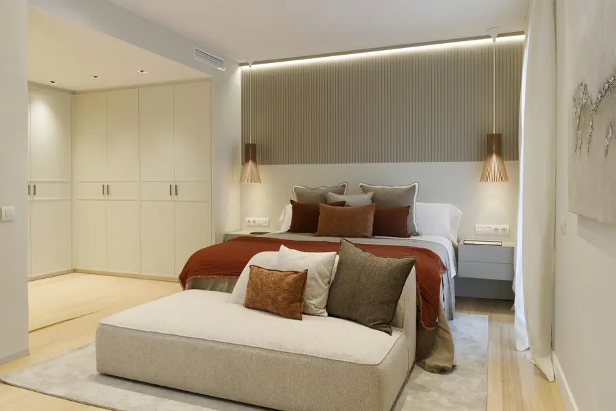 La suite principal integra descanso y vestidor Suite principal de la reforma Darder con cama, vestidor integrado y textiles cálidos
