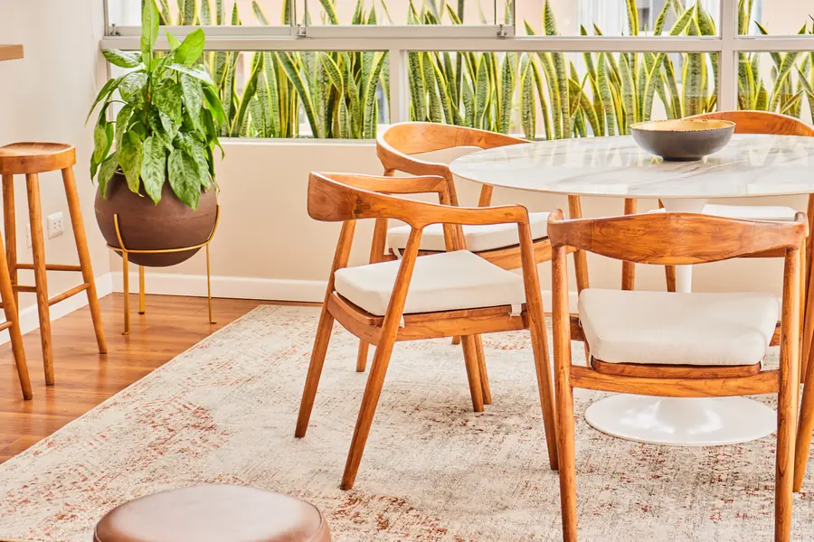Mesa de comedor junto a los ventanales y sillas de madera clara