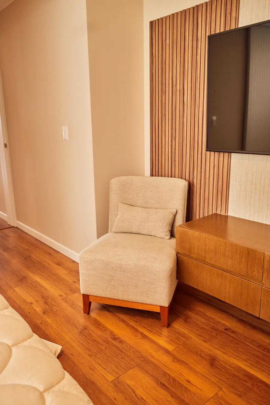 Rincón del dormitorio con sillón, mueble bajo y panel de listones