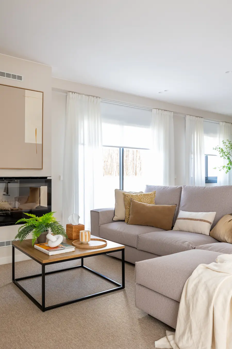 Salón con mueble de televisión, chimenea y sofá en tonos neutros