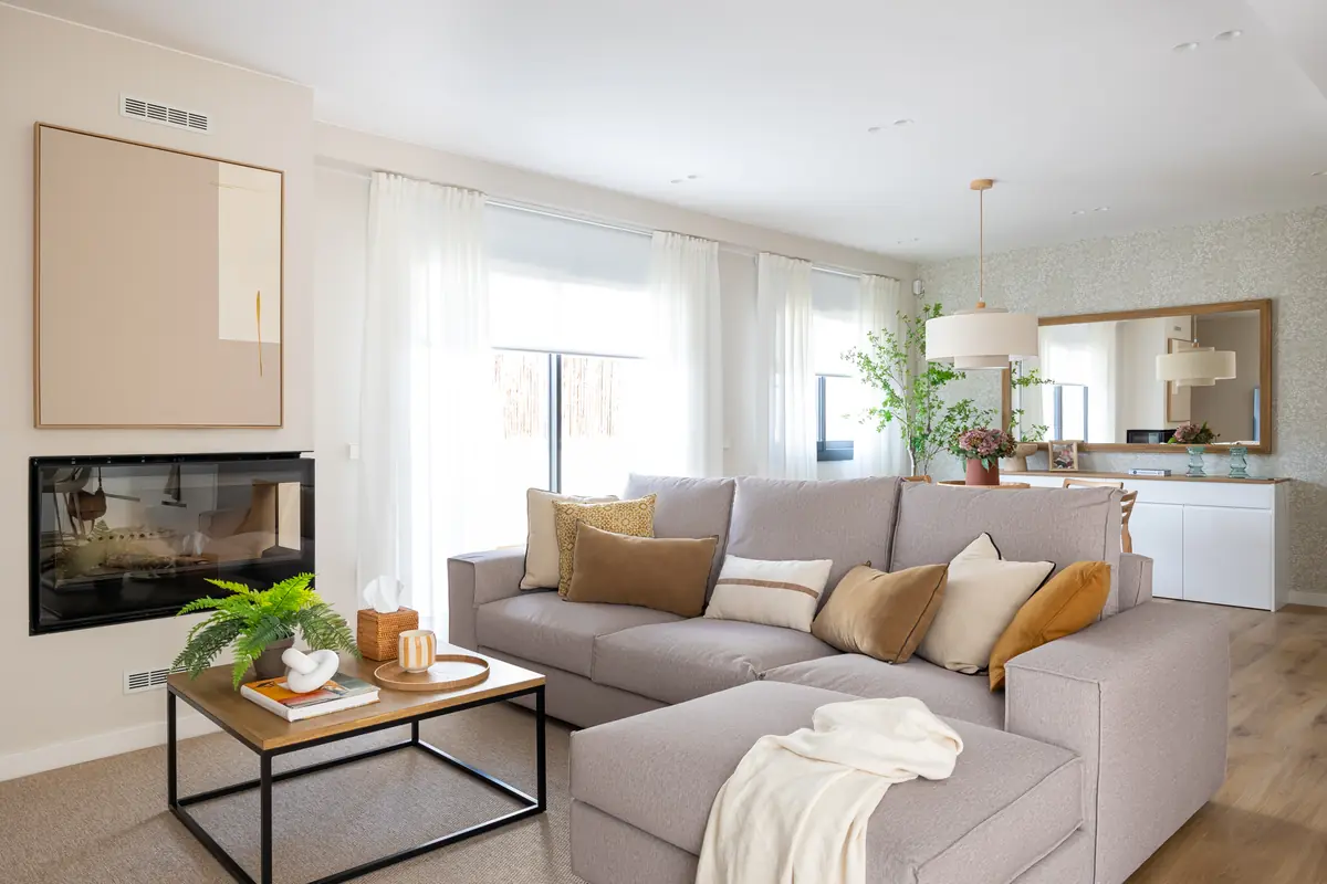 Salón principal de la vivienda Fontana con chimenea, sofá y grandes ventanales
