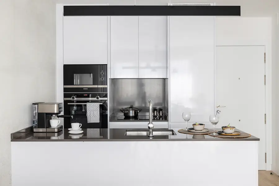 La cocina blanca incorpora una península multifunción Cocina blanca con península y encimera oscura en Málaga Centro