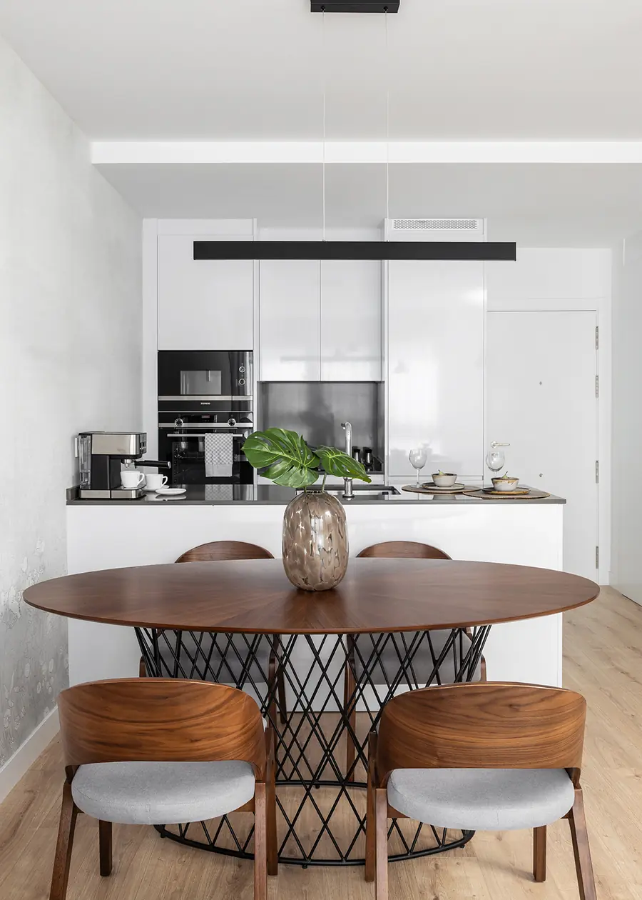 El comedor actúa como transición entre cocina y salón Comedor redondo frente a la cocina abierta de una vivienda en Málaga