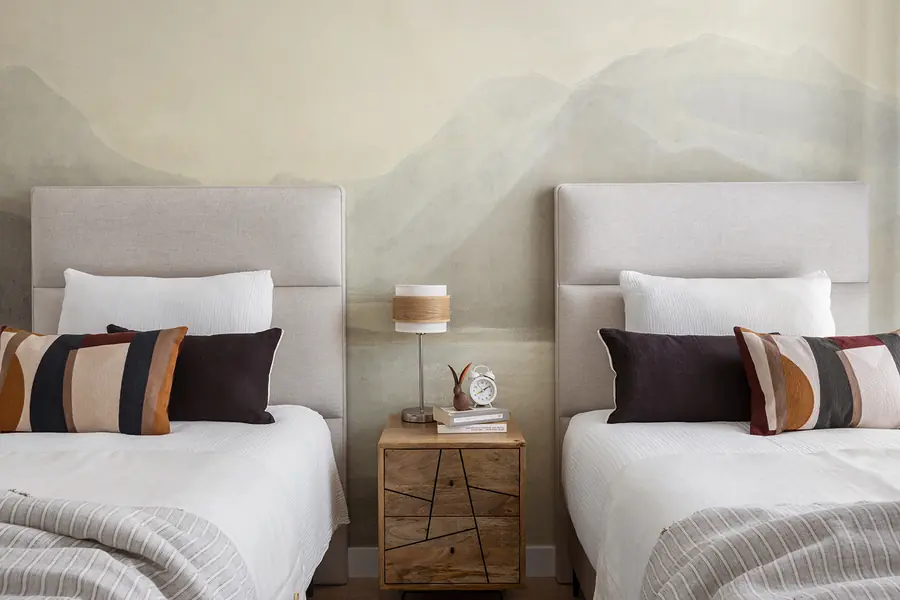 Un segundo dormitorio con paisaje mural Dormitorio con dos camas individuales y mural de montañas en tonos suaves