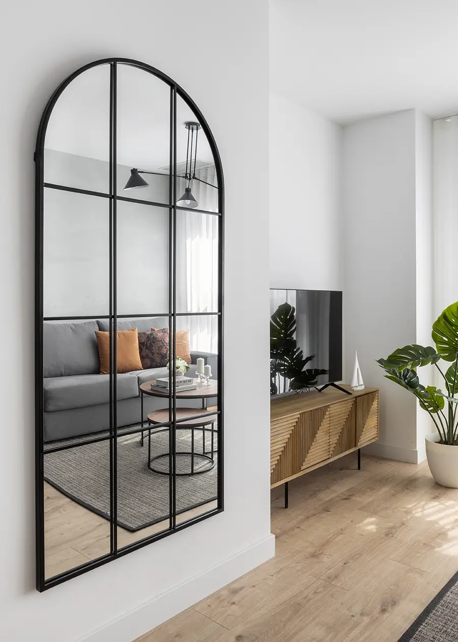 El espejo amplía visualmente la zona de día Espejo de arco y mueble de televisión en la zona de paso del salón