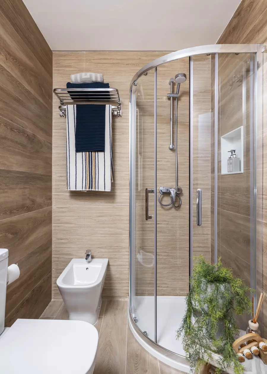 Una ducha curva que aligera el baño Ducha curva revestida con porcelánico efecto madera en el baño