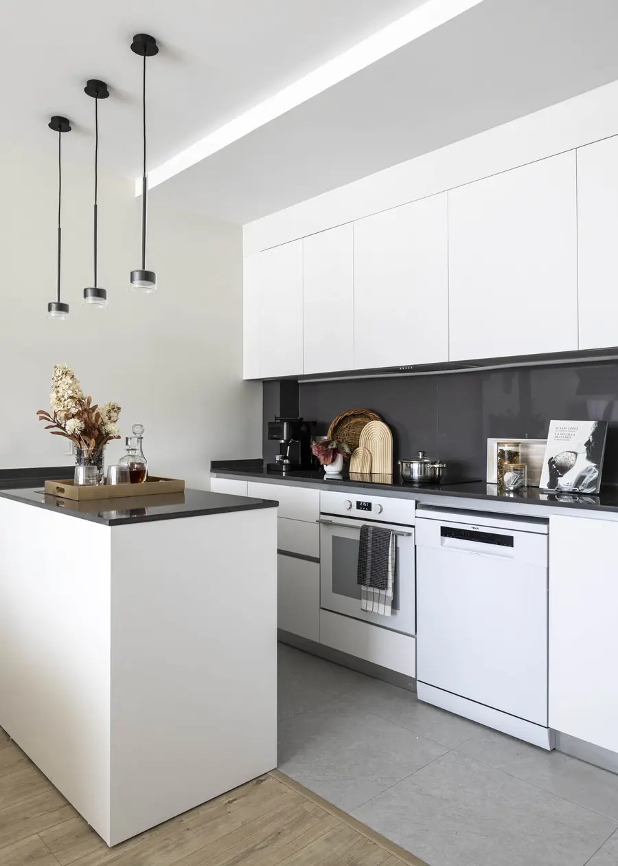 Una cocina blanca con almacenaje integrado Cocina lineal abierta con almacenaje integrado y electrodomésticos ocultos