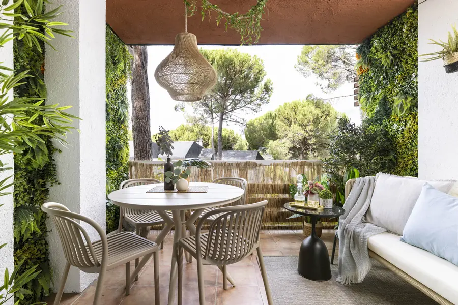 Comedor y descanso en la terraza Terraza con mesa redonda, sillas, sofá beige y lámpara colgante de fibra